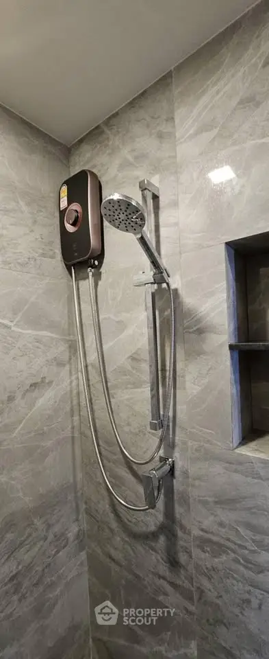 Modern bathroom with sleek showerhead and elegant gray marble tiles.