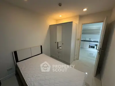 Cozy bedroom with modern wardrobe and view into sleek kitchen area.