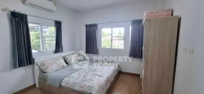 Cozy bedroom with large windows and air conditioning, featuring a comfortable bed and wooden flooring.