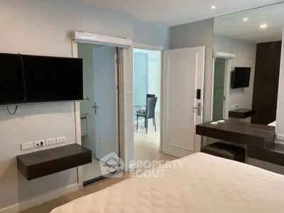 Modern bedroom with wall-mounted TV and sleek furniture in a stylish apartment.