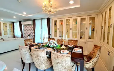 Luxurious dining room with elegant chandelier and plush seating in a modern open-plan living space.