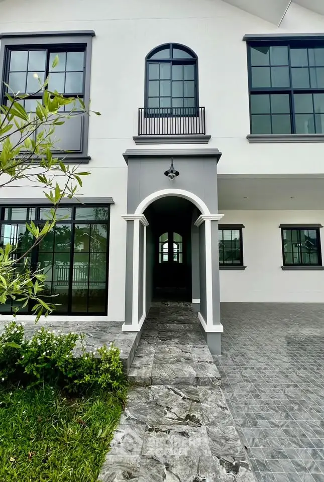 Elegant exterior of a modern house with arched entrance and large windows.