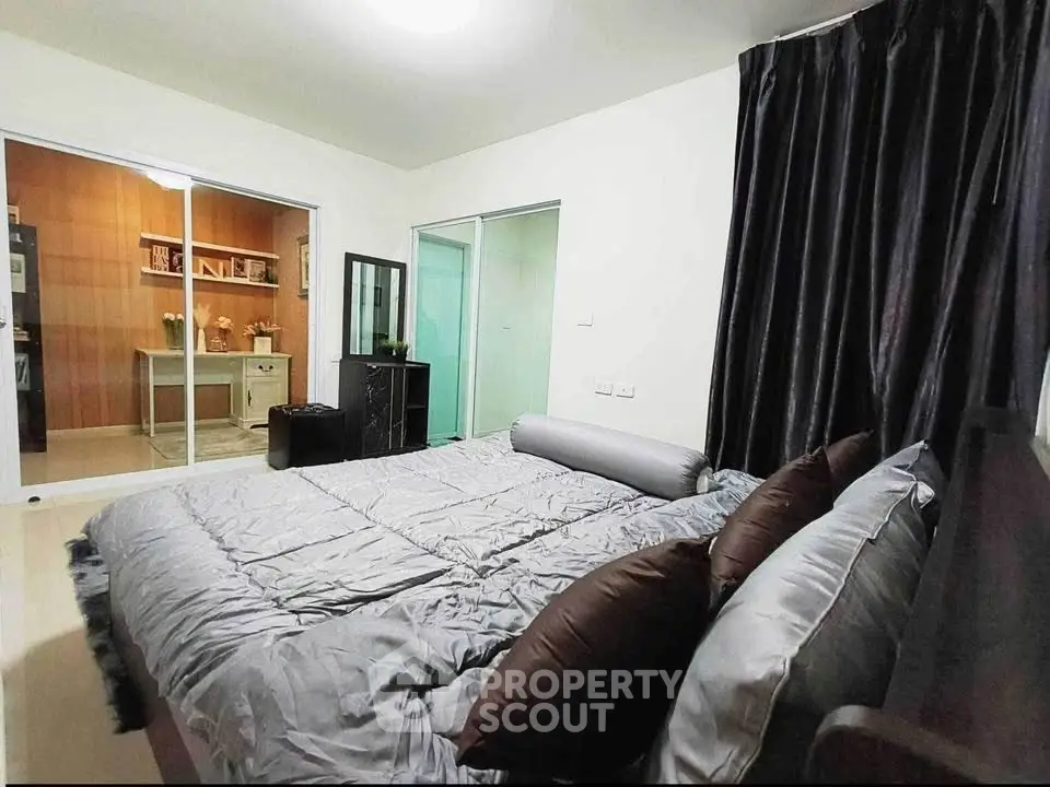 Spacious bedroom with modern decor and cozy bedding, featuring a view into a stylish study area.