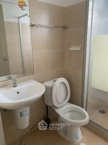 Modern bathroom with shower, sink, and toilet in neutral tones.