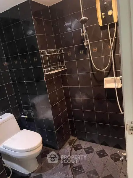 Modern bathroom with dark tiles and shower area in real estate property