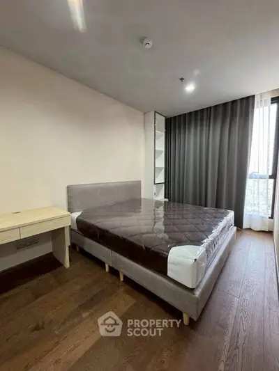 Spacious bedroom with modern design and large window offering natural light and city views.