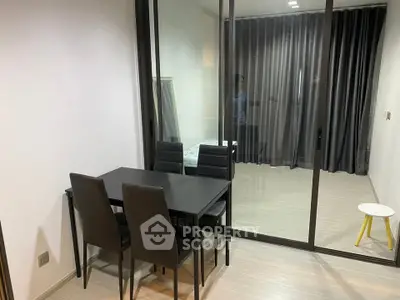Modern dining area with sleek black table and chairs, adjacent to a glass-enclosed room with curtains.