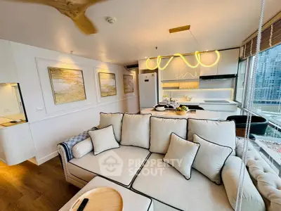 Luxurious modern living room with open kitchen and city view, featuring elegant decor and ample natural light.