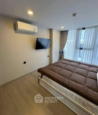 Modern bedroom with large window, air conditioning, and wall-mounted TV