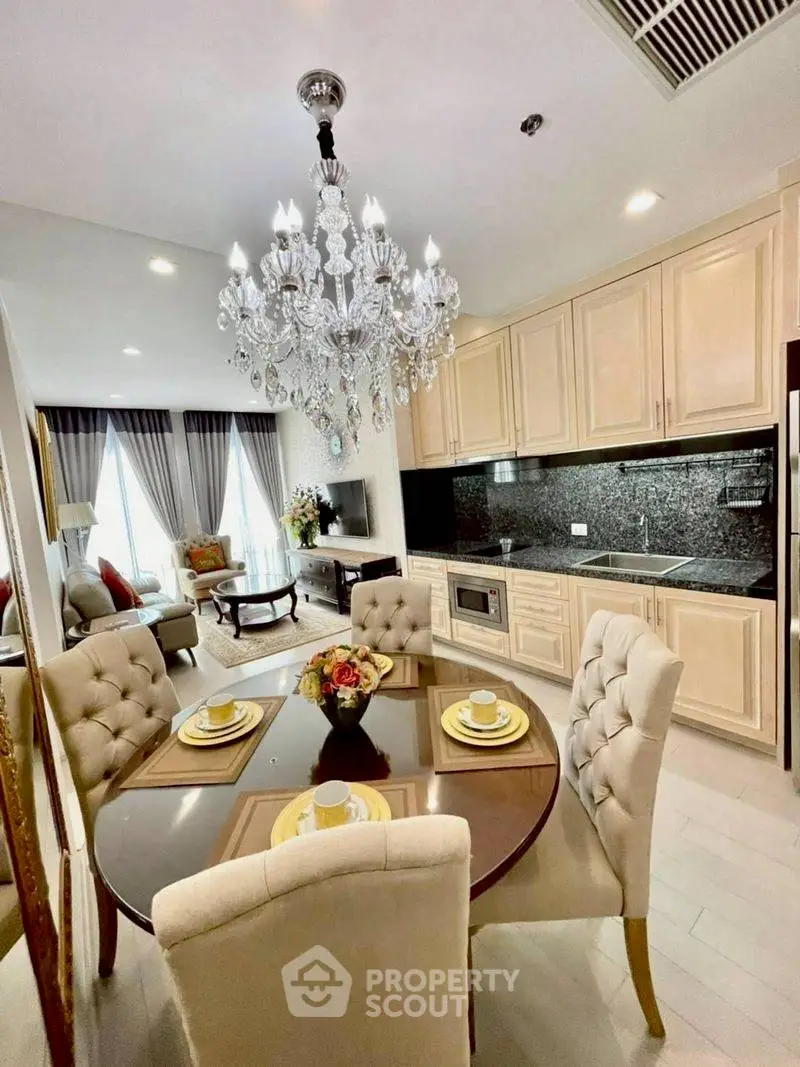 Luxurious open-plan living room and kitchen with elegant chandelier and modern furnishings.