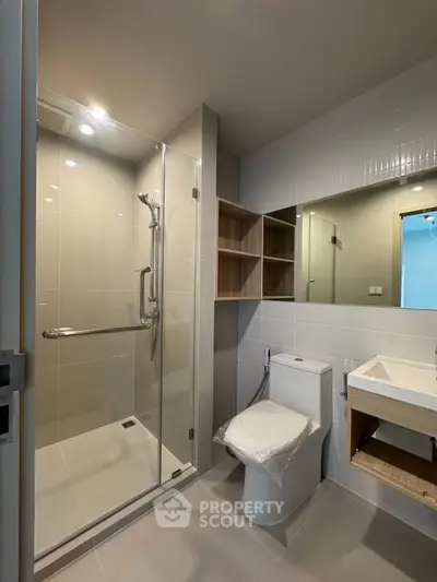 Modern bathroom with glass shower and sleek fixtures in a contemporary apartment.