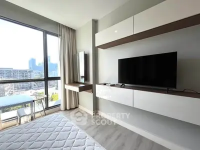 Modern bedroom with large window and city view, featuring sleek TV setup and stylish decor.