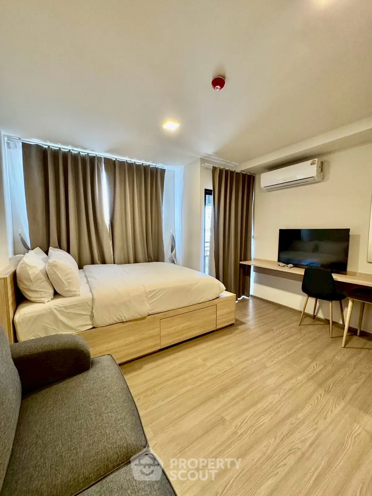 Modern bedroom with cozy decor and natural light, featuring a comfortable bed and stylish workspace.