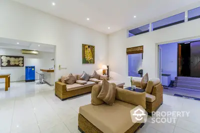 Spacious living room with high ceilings, modern furniture, and an open layout leading to a sleek kitchen, perfect for entertaining.