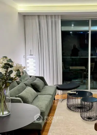 Modern living room with stylish furniture and floor-to-ceiling windows leading to a balcony.