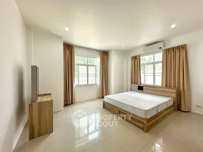 Spacious bedroom with natural light and modern furnishings in a serene setting.