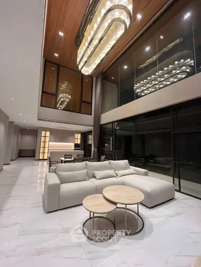 Luxurious modern living room with high ceilings, elegant chandelier, and stylish furniture.