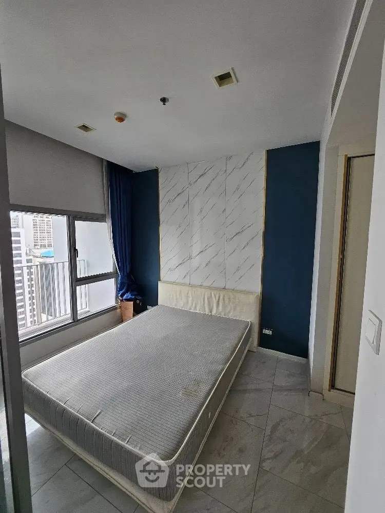 Modern bedroom with city view, featuring a minimalist design and large window.