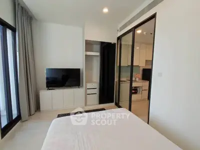 Modern bedroom with TV and open kitchen view in a stylish apartment