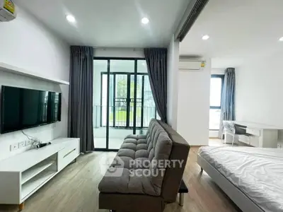 Modern studio apartment with balcony, featuring sleek furniture and abundant natural light.