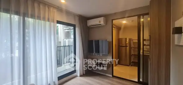 Modern living room with balcony and kitchen view, featuring sleek design and natural light.