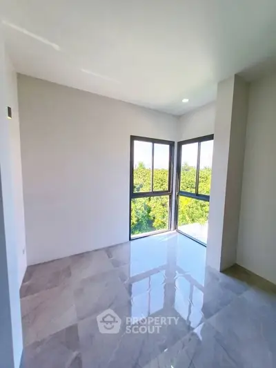Bright corner unit with large windows and marble flooring offering a stunning green view.