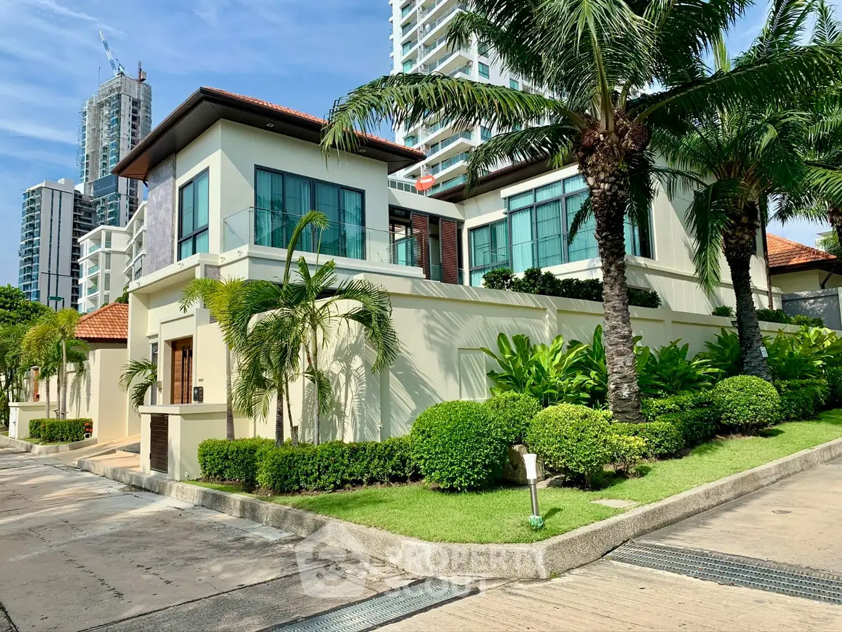 Luxurious modern villa with lush landscaping and palm trees in an upscale neighborhood.