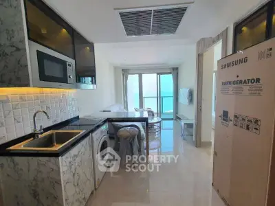 Modern kitchen with marble countertops, stainless steel appliances, and a view of the ocean through the balcony doors, perfect for culinary enthusiasts.