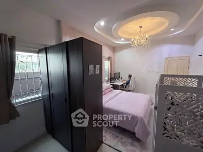Elegant bedroom with chandelier and modern decor, featuring a cozy workspace and ample natural light.