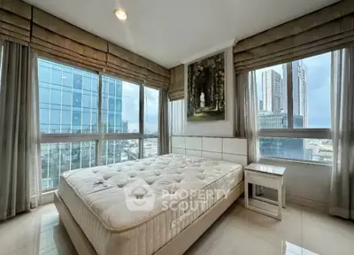 Luxurious bedroom with panoramic city views and modern decor in high-rise apartment.