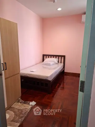 Cozy bedroom with wooden flooring and single bed, perfect for a minimalist lifestyle.