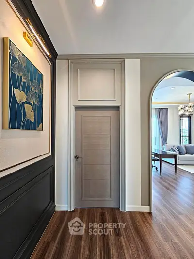 Elegant interior hallway with modern decor and view into a stylish living room with wooden flooring.