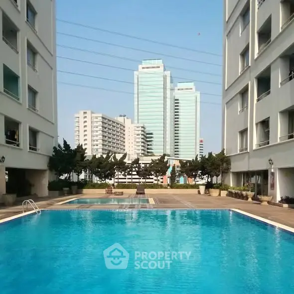 Luxurious apartment complex with a stunning pool and cityscape view.