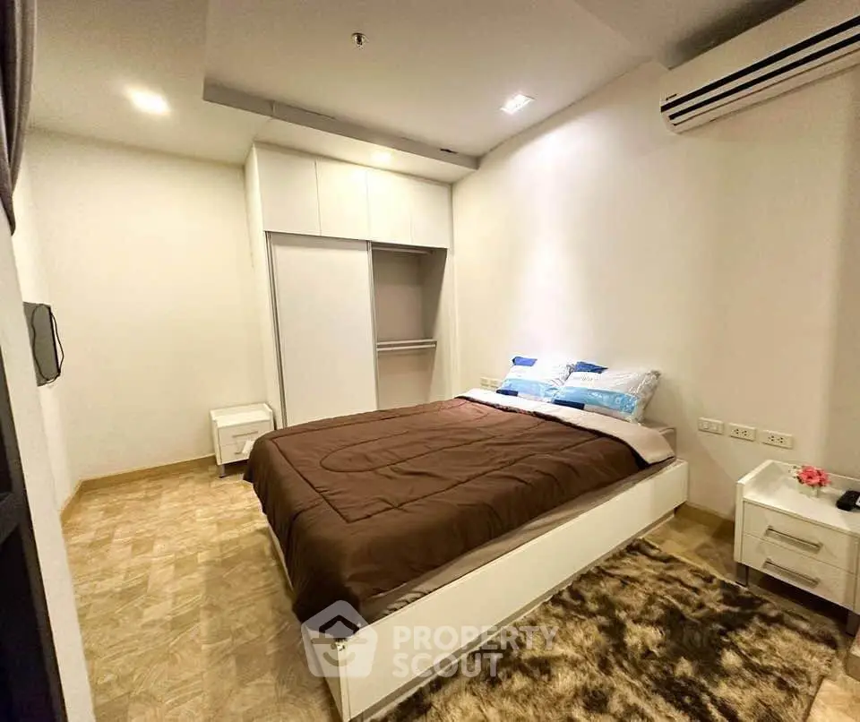 Cozy bedroom with modern design, featuring a comfortable bed, built-in wardrobe, and air conditioning.