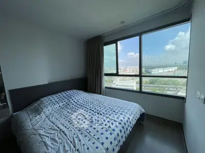 Spacious bedroom with large window offering stunning city views, perfect for urban living.