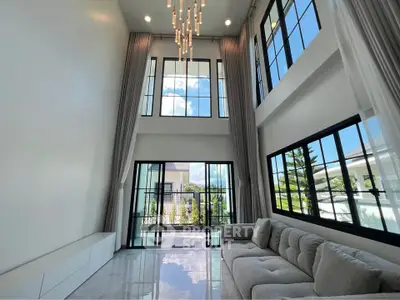 Luxurious high-ceiling living room with large windows and elegant chandelier