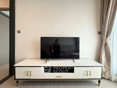 Modern living room with sleek TV stand and flat-screen TV, elegant curtains, and neutral decor.