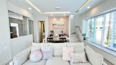 Elegant living room with cozy sofa and dining area, featuring large windows and modern decor.