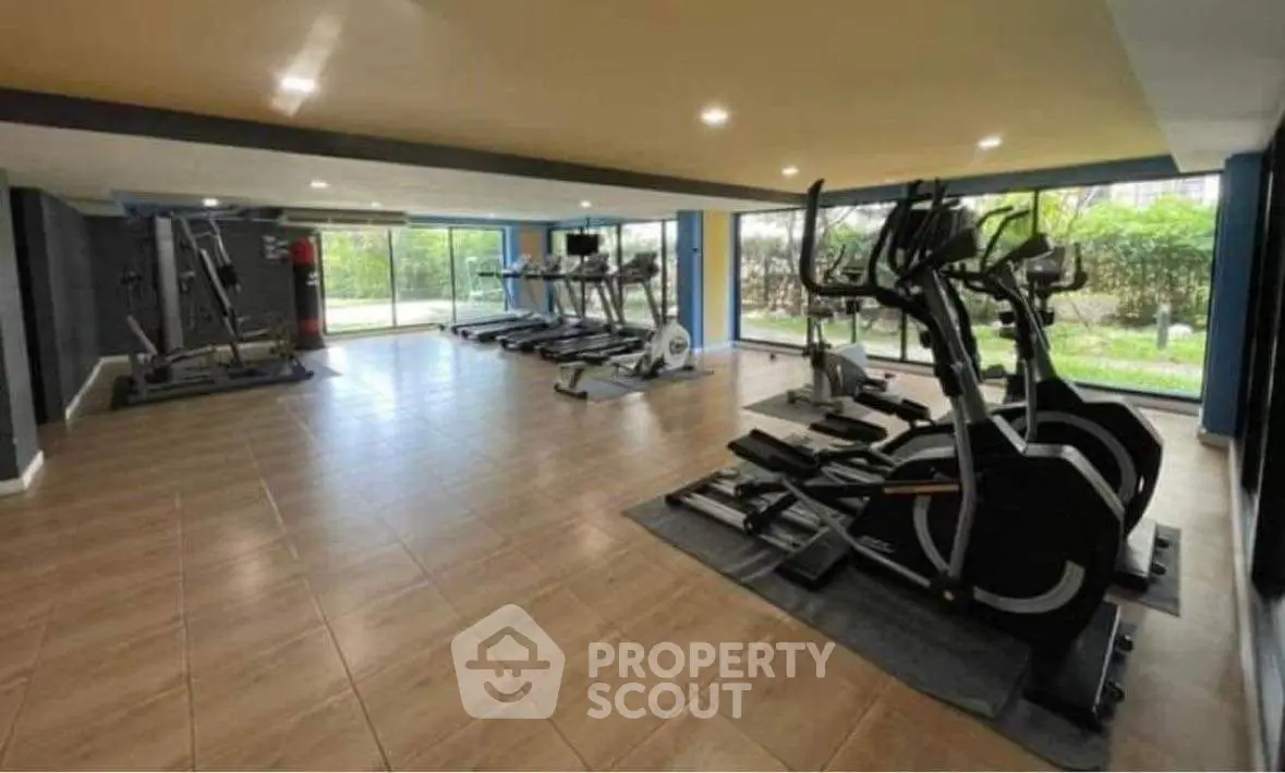 Spacious gym with modern equipment and large windows offering garden views.