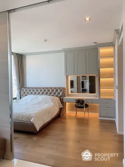 Modern bedroom with elegant design and built-in desk, featuring wooden flooring and natural light.