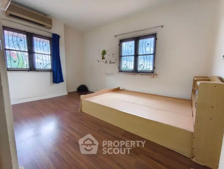 Spacious bedroom with wooden flooring and natural light