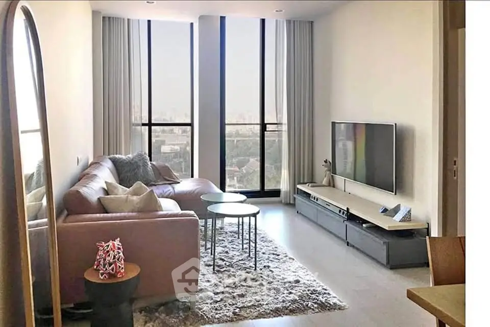 Modern living room with large windows and stylish furniture in a high-rise apartment.