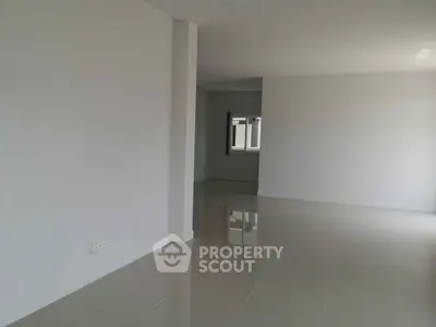 Spacious empty room with glossy tiled floors and neutral walls, ready for customization.