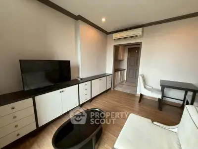 Modern living room with sleek furniture and wooden flooring, featuring a TV and air conditioning.