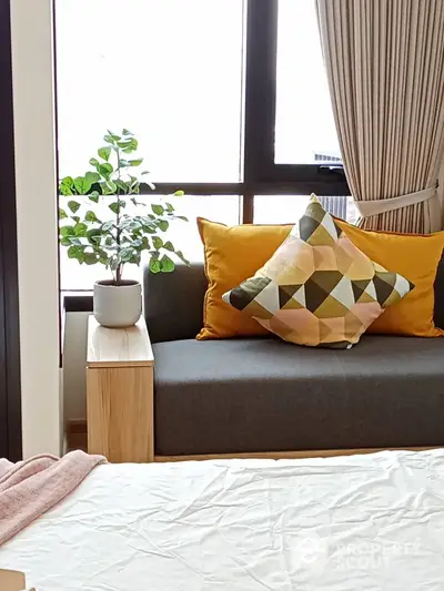 Cozy bedroom with stylish sofa and geometric cushions by a bright window