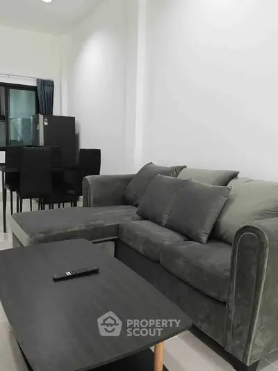 Modern living room with sleek gray sofa and dining area, perfect for urban living.