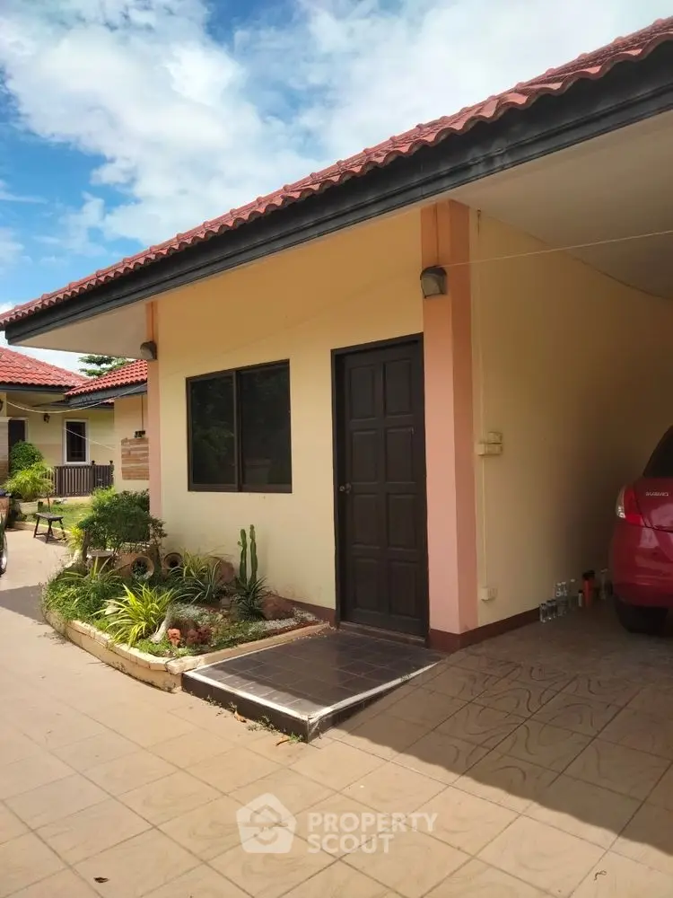 Charming single-story home with red roof and garden, perfect for cozy living.