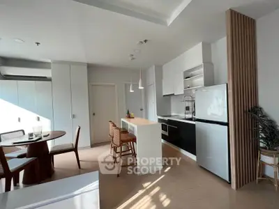 Modern kitchen with sleek design and dining area, featuring natural light and contemporary furniture.