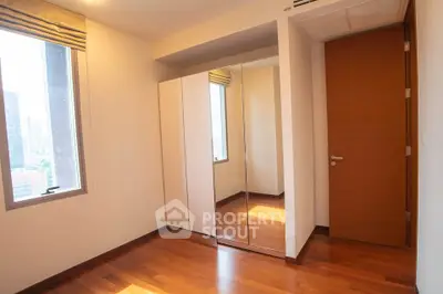 Bright bedroom with wooden flooring and mirrored wardrobe in modern apartment