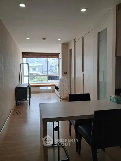 Modern apartment interior with sleek dining area and large window view.